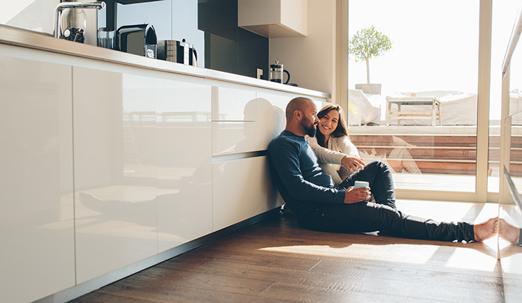 Two people sitting on the floor in a sunny kitchen