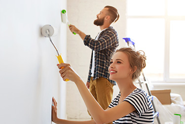 Two people paining a wall with a roller